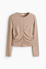 Top de manga larga de punto suave, color beige, con escote redondo y diseño ajustado con costura fruncida en el centro y los costados para lograr un efecto drapeado.