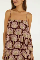 Vestido largo bordó con estampado paisley, escote recto y tirantes finos. Presenta un diseño de múltiples volantes superpuestos con hilos metalizados que aportan movimiento y textura.