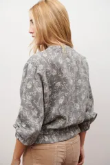 Bomber de tela liviana color beige con textura sutil, cierre frontal completo, mangas largas con puños elásticos y cordón ajustable en el ruedo.