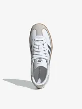 Zapatillas Adidas Samba OG blancas con detalles en plateado y suela de goma color caramelo.