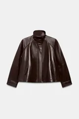 Chaqueta bomber de piel color marrón oscuro, con cuello alto, cierre frontal con cremallera y solapa con botones ocultos. Presenta mangas largas, bolsillos delanteros y un diseño de corte recto.