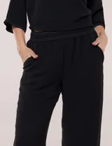 Pantalón pull-on de color beige con caída fluida, cintura elastizada fruncida, bolsillos laterales funcionales y pierna amplia de corte wide leg.