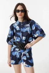 Short de tiro alto con estampado floral en tonos azules y blancos. Presenta pretina estructurada, pliegues frontales, bolsillos laterales y cierre frontal con ganchito interno metálico.