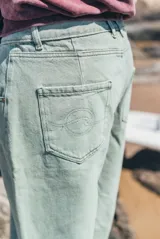 Pantalon de denim estilo wide leg en color verde lavado, con corte holgado y diseño de tiro medio. Presenta costuras reforzadas y detalle de marca bordado verticalmente en la pierna.