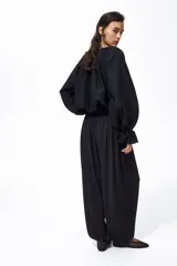 Pantalón negro de tiro alto confeccionado en punto interlock pesado. Cuenta con cintura elástica con pliegues cosidos alrededor, diseño de piernas barrel y puños elásticos ceñidos en los tobillos.