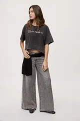 Remera gris de fit amplio, con mangas cortas y cuello redondo. Presenta efecto lavado y estampa frontal con aplicación de strass con la frase "fiesta mode on".