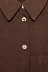 Camisa de corte oversize color marrón, con cuello solapa, mangas anchas por debajo del codo y bolsillo delantero de plastrón. Cierre frontal con botones.