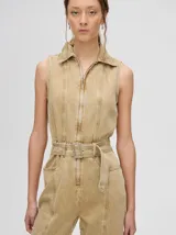 Mono largo de denim azul con corte holgado, recto en las piernas y entallado en el tronco. Tiene cuello camisero, cierre frontal con cremallera y cinturón ajustable.