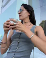 Pulsera artesanal compuesta por una serie de cuentas metálicas irregulares ensartadas en un hilo de algodón natural. Diseño rústico y minimalista.