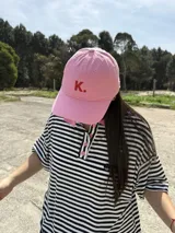 Gorro de béisbol rosa con la letra K bordada en rojo en el frente.