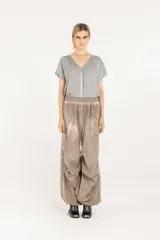 Pantalón amplio de popelina de algodón y satén de viscosa, en tono gris con efecto de teñido en frío. Presenta cintura elastizada, diseño de pierna ancha con frunces laterales y cordón de ajuste en el ruedo que permite fruncirlo en los tobillos.
