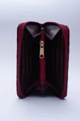 Billetera marrón tipo sobre con cierre de cremallera, confeccionada en cuero con textura tipo cocodrilo y forro textil rojo. Cuenta con múltiples ranuras para tarjetas, documentos y billetes.