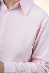 Camisa de algodón color rosado, con cuello camisero, manga larga y cierre frontal de botones.