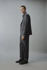 Pantalón de traje regular fit color gris oscuro, confeccionado en tejido con lana, con bolsillos frontales y bolsillos traseros de doble vivo con botón. Cierre frontal con cremallera y botón.