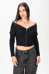 Sweater corto de tejido acanalado en color bordó, con cuello tipo off-shoulder solapado y cierre frontal completo con cremallera.