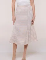 Falda midi evasé de color beige con diseño a rayas horizontales y verticales blancas, cintura alta elastizada y caída fluida.