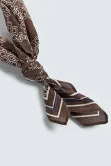 Pañuelo cuadrado de algodón, color marrón oscuro, con estampado geométrico repetitivo en color beige claro y bordes definidos por líneas finas blancas y moradas.
