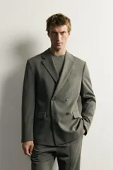 Blazer cruzada de traje color verde militar, de corte regular fit, con solapas de muesca, cierre frontal de doble botonadura, bolsillos con solapa en la cadera y bolsillo de vivo en el pecho.