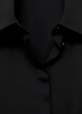Camisa básica de tejido fluido y color negro, con diseño recto, cuello camisero, manga larga con puños abotonados y cierre delantero con botones.