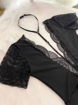 Body entallado de lycra color negro, con escote pronunciado decorado con encaje y microtul. Presenta mangas cortas de encaje y un collarín regulable desmontable integrado al diseño.