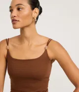 Body femenino ajustado, sin mangas, color verde oliva, con escote cuadrado y breteles finos dobles adornados con piezas decorativas. El tejido es texturizado.