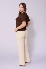 Jean de corte wide leg en color beige, con tiro alto y cierre frontal con botón y cremallera. Presenta un diseño de cinco bolsillos y costuras reforzadas.