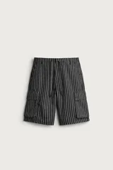 Bermuda cargo relaxed fit confeccionada en denim de mezcla de algodón y lino, con diseño de rayas verticales grises y negras. Cuenta con bolsillos laterales tipo cargo con solapa y cierre frontal con cremallera y botón.