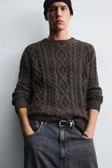 Jersey de punto con diseño de trenzas, cuello redondo y manga larga. Presenta un acabado en rib en puños y ruedo, con un efecto de lavado que le otorga una apariencia única.
