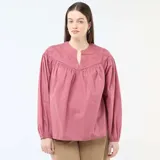 Blusa color rojo con escote en V y cuello mao. Presenta detalles de bordados tonales en el canesú delantero, mangas largas abullonadas y un diseño amplio y fluido.