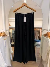 Pantalón ancho y fluido color negro, de corte holgado, con cintura elástica fruncida y cordón ajustable delantero.