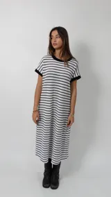Vestido midi de tejido de punto con diseño de rayas horizontales en blanco y negro. Presenta un corte holgado, cuello redondo, mangas cortas con bordes en negro y un tajo lateral en el ruedo.