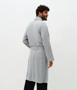 Bata de baño larga de tejido de poliéster texturizado con relieve, cuello estilo chal, mangas largas, bolsillos frontales y lazo para ajustar en la cintura.
