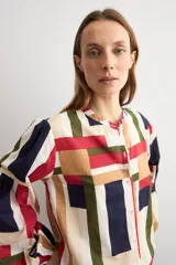 Camisa de manga larga con estampado geométrico multicolor en tonos beige, rojo, azul marino y verde, cuello mao y cierre frontal con botones.