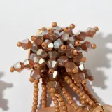 Aros colgantes con base de cuentas color marrón y colgantes de cuentas color naranja.