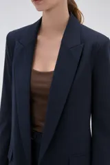Blazer de corte holgado con diseño de rayas verticales, cuello solapa y cierre frontal con un botón. Presenta bolsillos laterales con solapa y mangas largas.