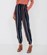 Pantalón Marfinno de viscosa azul marino con diseño de rayas verticales en tonos naranja, blanco y tostado. Cuenta con cintura elástica con cordón de ajuste, bolsillos laterales y terminaciones elásticas en los tobillos.