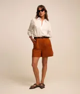 Short de sastrería Cortelle color tostado, con pliegues en la parte delantera, trabillas en la cintura y cierre frontal. Incluye un cinturón delgado de PU negro con hebilla metálica.
