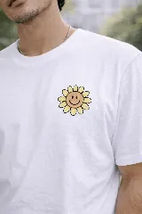 Remera blanca de manga corta con estampado frontal pequeño de una flor con cara sonriente en tonos amarillos.