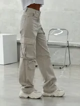 Pantalón cargo color beige, de corte recto y tiro alto, con bolsillos laterales con solapa y bolsillos delanteros.
