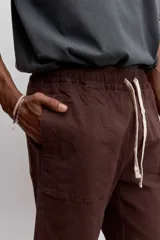 Pantalon de corte recto en color marron, confeccionado en tela resistente, con bolsillos laterales tipo parche y cierre frontal.