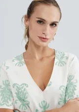 Blusa color beige con estampado de hojas color verde agua, escote en V y mangas cortas.