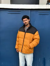 Campera puffer color mostaza con cuello alto y cierre frontal con cremallera.