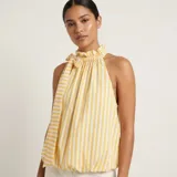 Musculosa sin mangas de rayas amarillas y blancas, con cuello halter alto fruncido, detalle de lazo lateral y dobladillo inferior ajustado.
