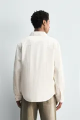 Sobrecamisa de corte regular confeccionada en denim de algodón, con cuello solapa, manga larga con puños abotonados y cierre frontal de botones. Presenta dos bolsillos frontales de plastrón con solapa y bajo con aberturas laterales.