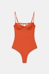 Bañador de una pieza color naranja con acabado satinado, escote redondo con aros integrados y tirantes finos ajustables. Presenta una espalda pronunciada con tiras cruzadas y cierre de lazada.