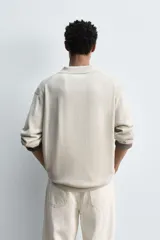 Polo de punto regular fit en color beige, confeccionado con una mezcla de algodón y cáñamo. Presenta cuello solapa con abertura frontal, manga larga y acabados en rib.