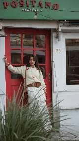 Buzo tejido a mano de lana merino color blanco marfil, con diseño holgado, cuello redondo, mangas largas y detalles de corazones rojos dispersos.