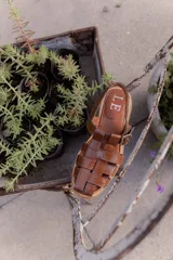 Sandalias de cuero con tiras entrecruzadas, suela plana y hebilla lateral.