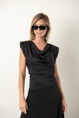 Blusa negra con lunares blancos, cuello drapeado y corte ajustado.