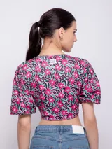 Top estampado con flores rosas, hojas verdes y líneas negras, de manga corta abullonada con nudo en el escote.